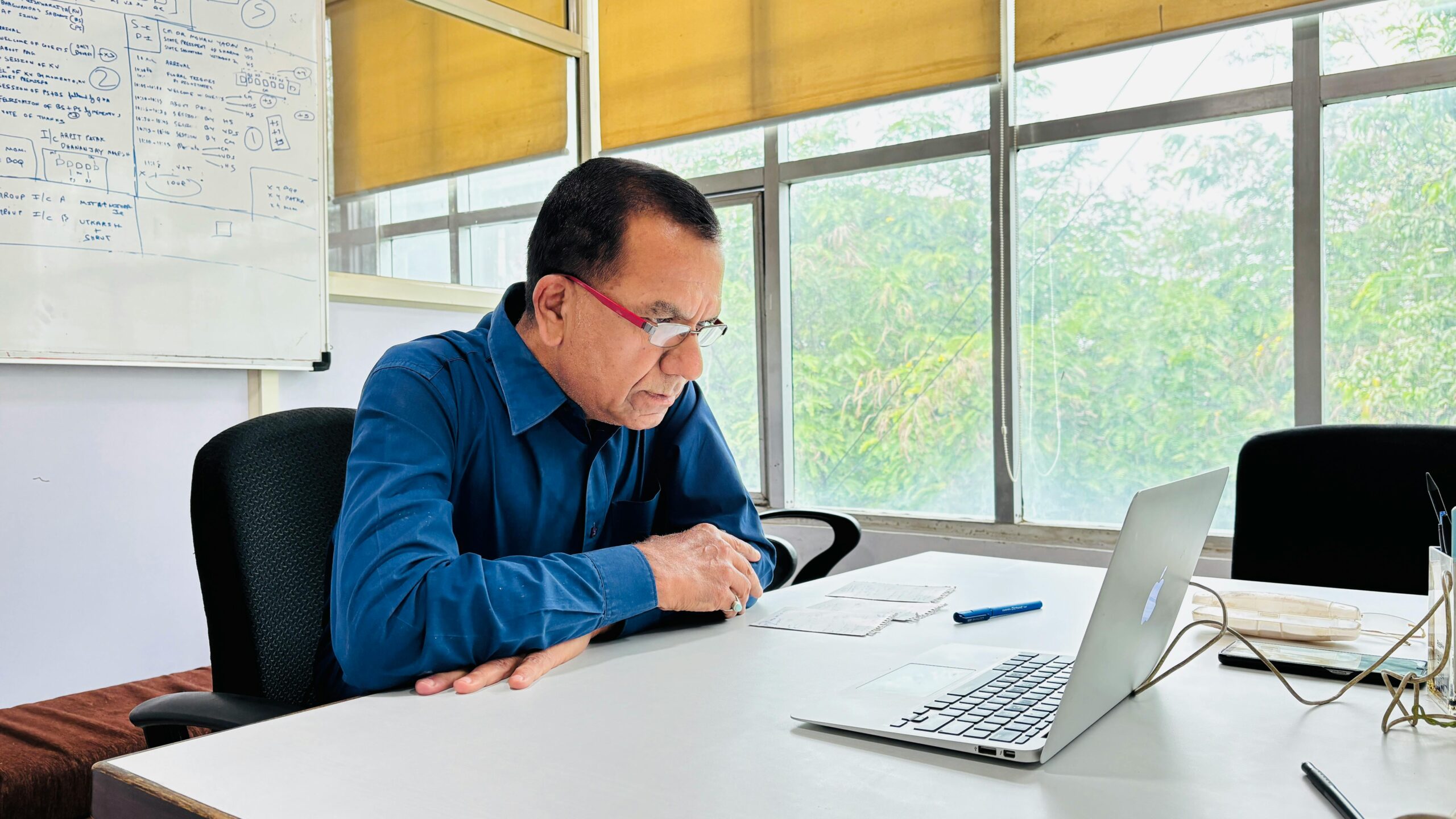 pexels-photo-31454218-31454218 Focused man in blue shirt works intently on a laptop in a bright office setting.