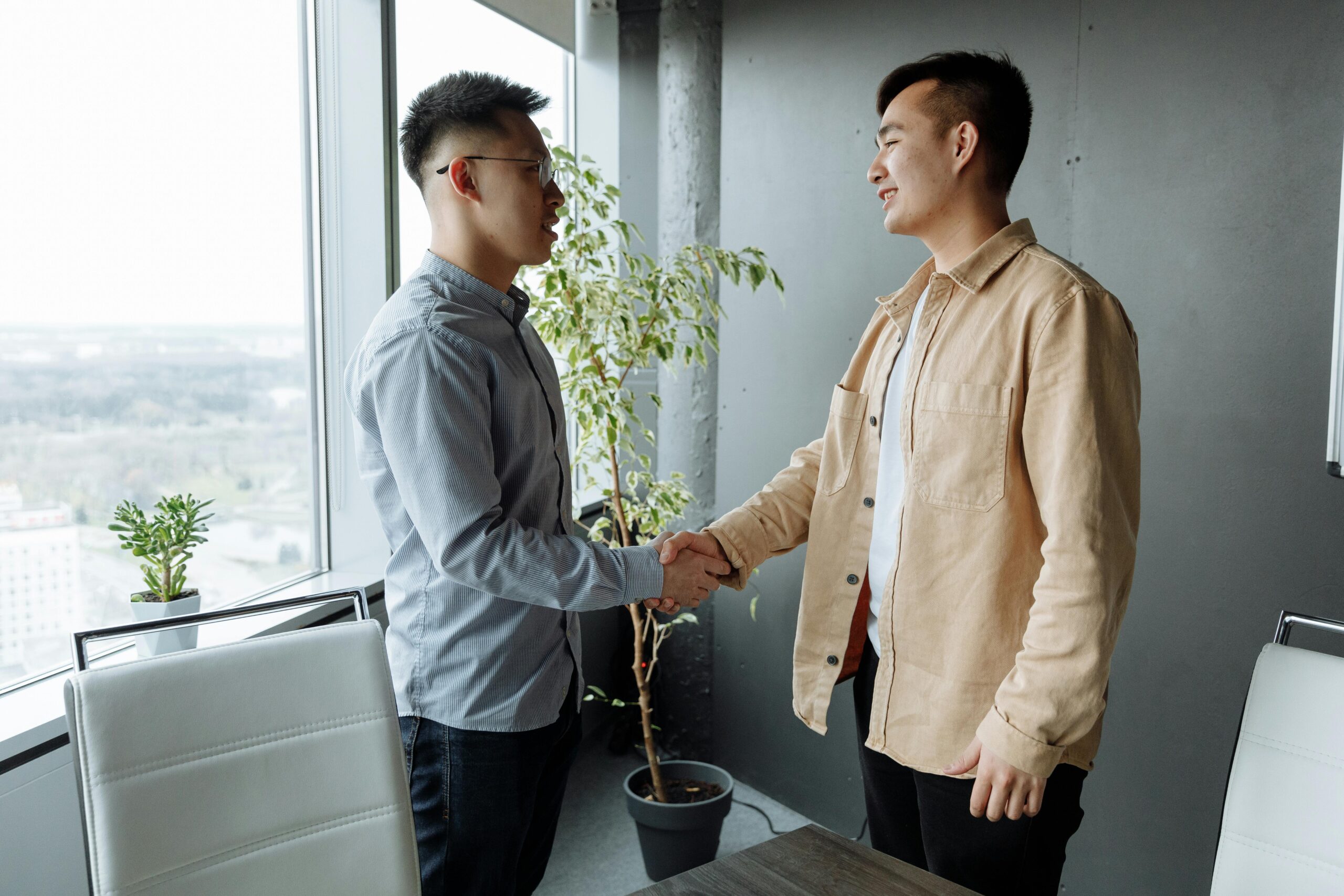 Two businessmen shaking hands in a modern office setting, symbolizing a successful business partnership.